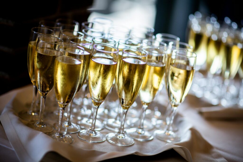 clear wine glasses with gold liquid on white cloth covered table